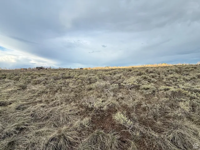 Expansive natural landscape featuring varied terrain and distant structures under a broad sky