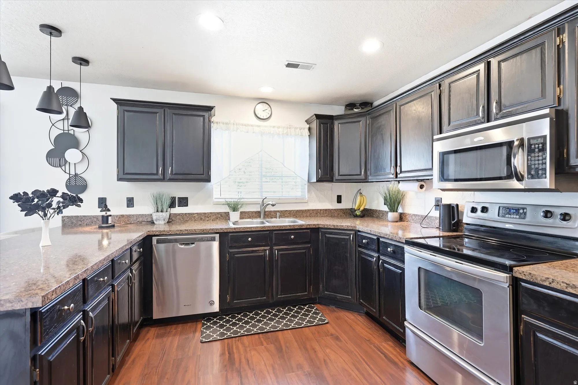Well-appointed kitchen featuring dark wood cabinetry and wood-finish flooring