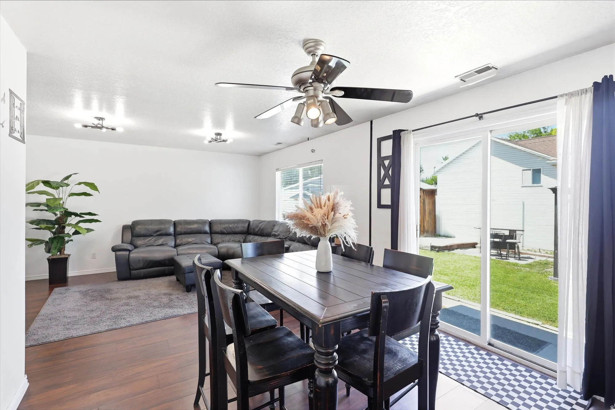 Dining area with wood-finish flooring, a contemporary ceiling fan, and sliding glass doors leading to a grassy yard