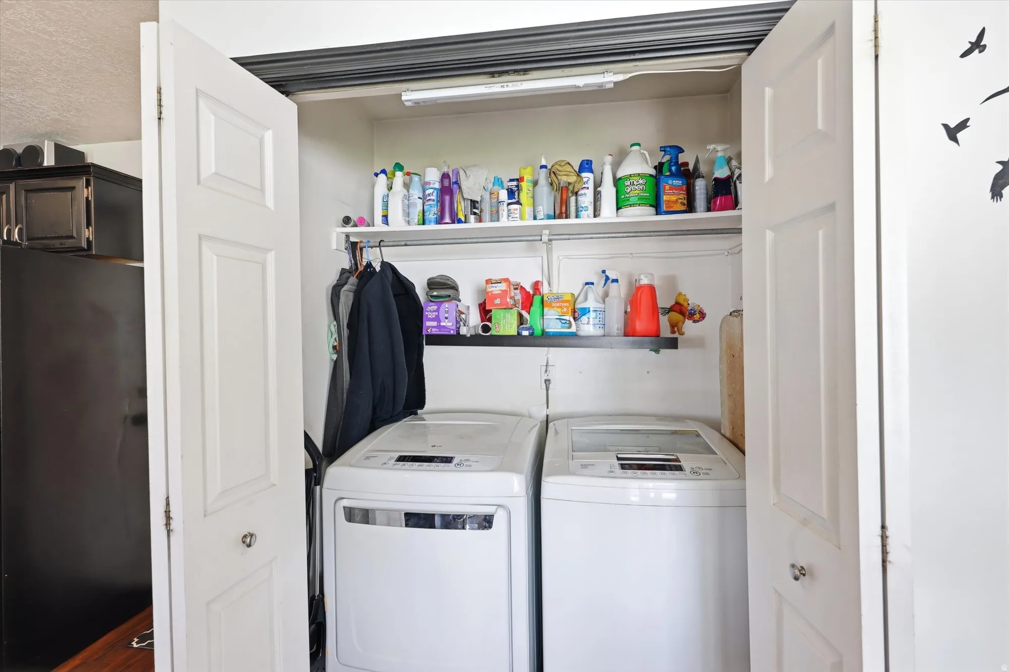 Laundry closet featuring bifold panel doors, built-in shelving, and a hanging rod