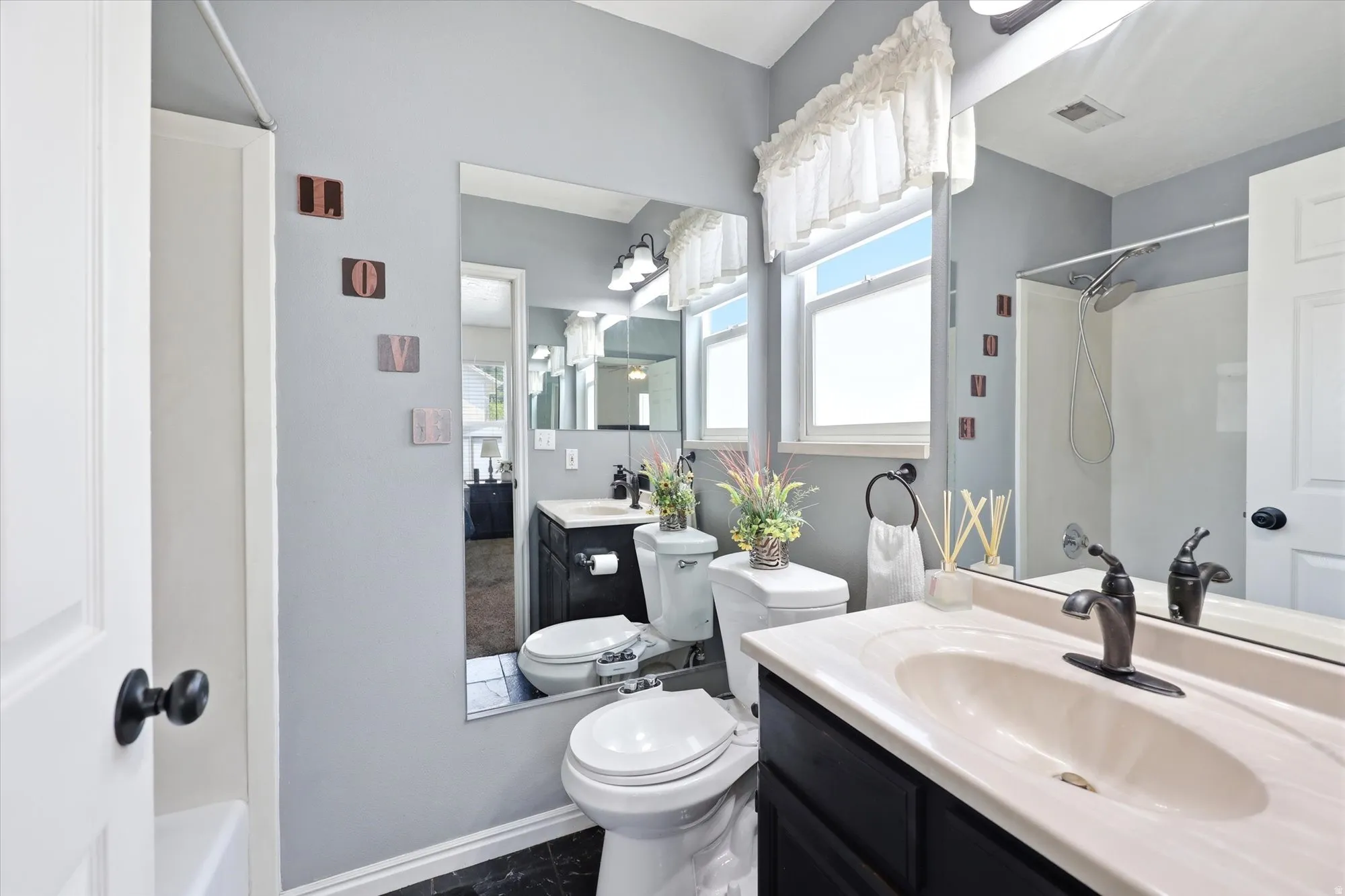 Bathroom featuring a single vanity with an integrated sink, dark cabinetry, and bronze-finish hardware