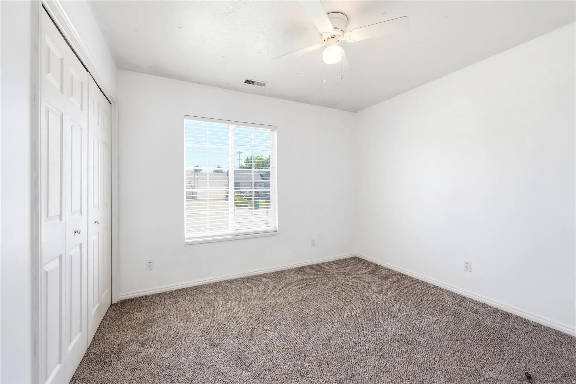 Room featuring neutral carpeting, white walls, a ceiling fan with integrated lighting, and a window with horizontal blinds