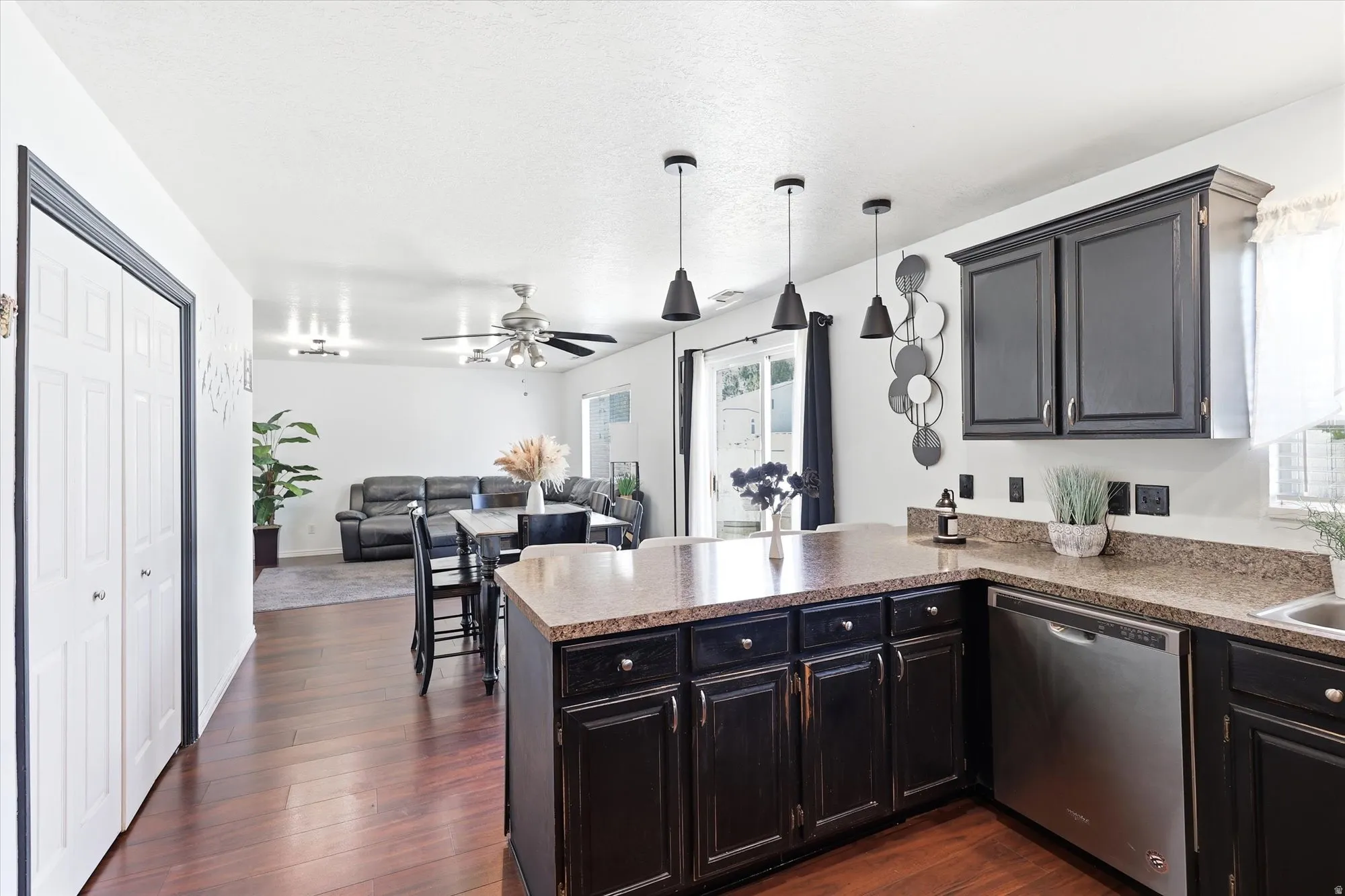 Kitchen island with pendant lighting, dark cabinetry, and stone-finish countertops