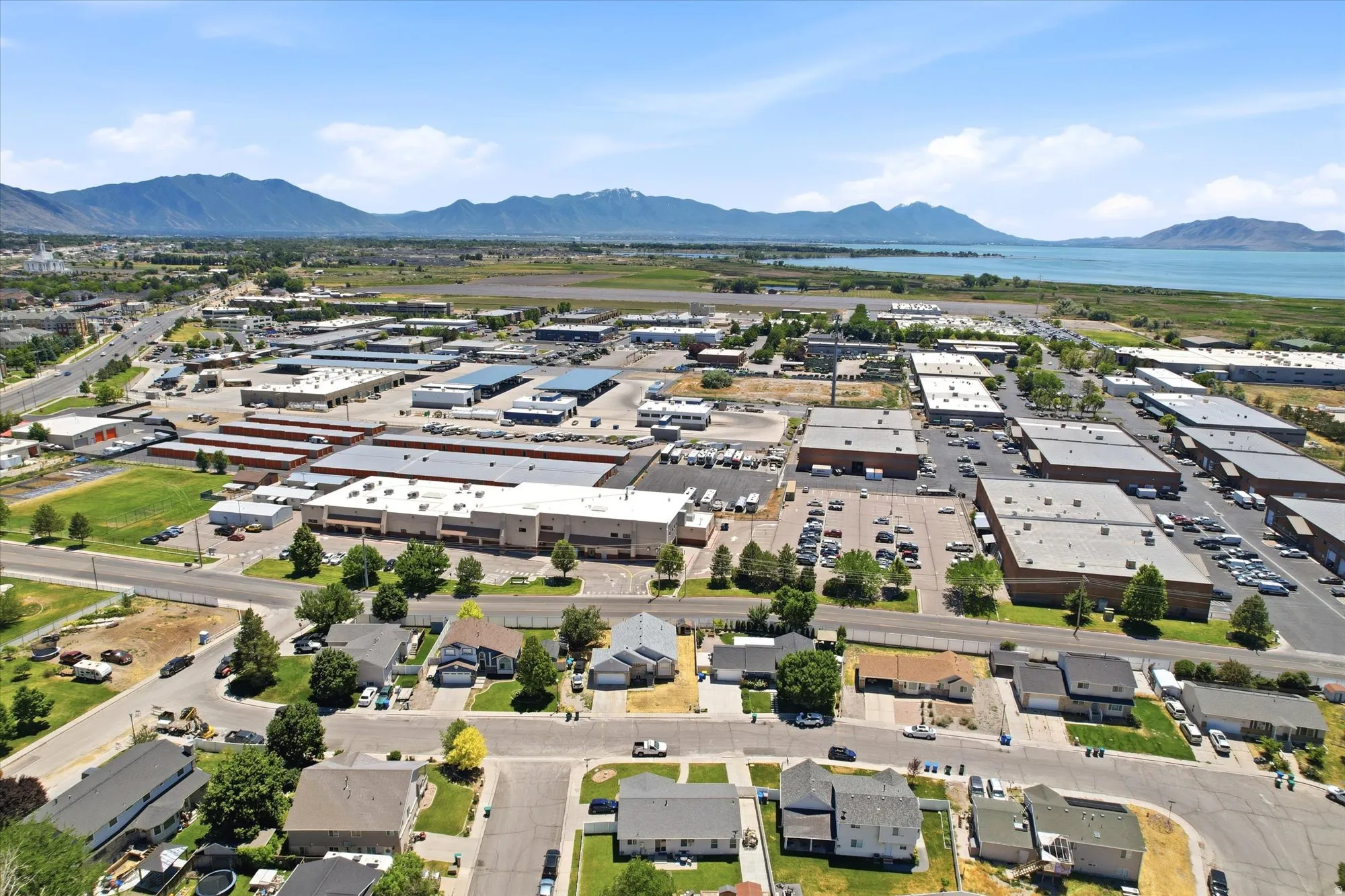Aerial perspective showcasing a mixed-use area with commercial buildings, residential properties, and a large body of water in the background