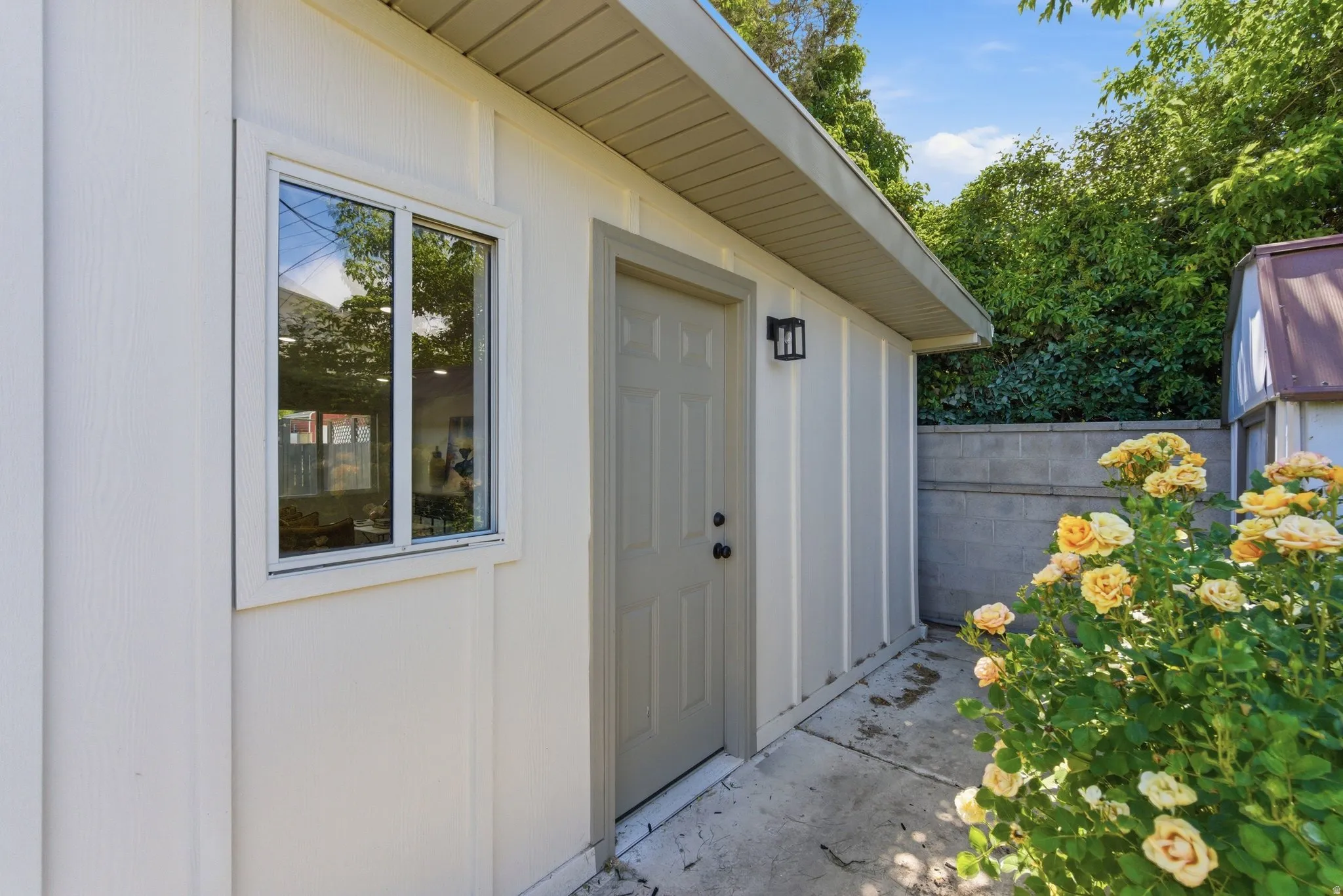 Exterior wall featuring vertical siding, a window, and a door with a contemporary wall sconce