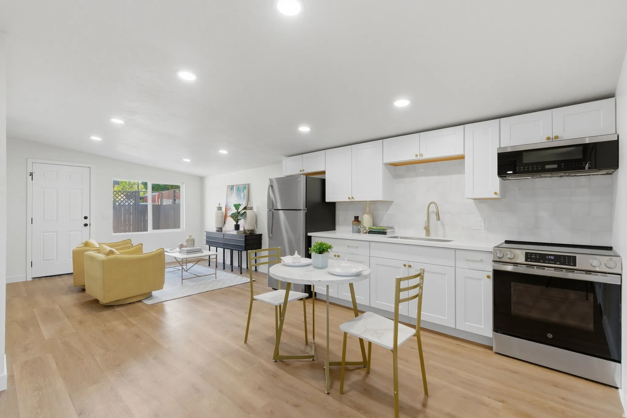 Open-concept living area featuring wood-finish flooring, recessed lighting, and a white paneled door