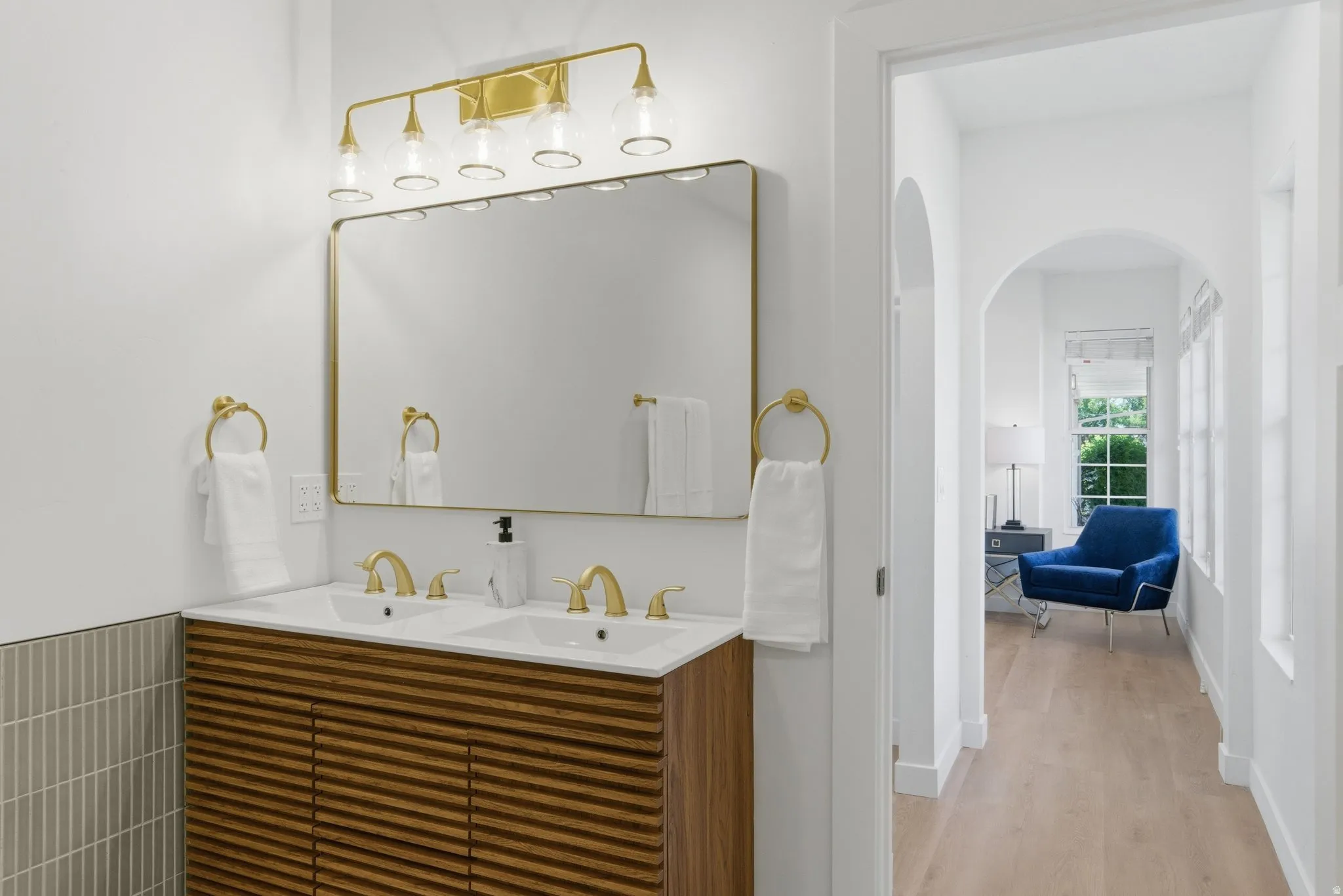 Dual vanity with gold-tone hardware, rectangular mirror, and decorative light fixture