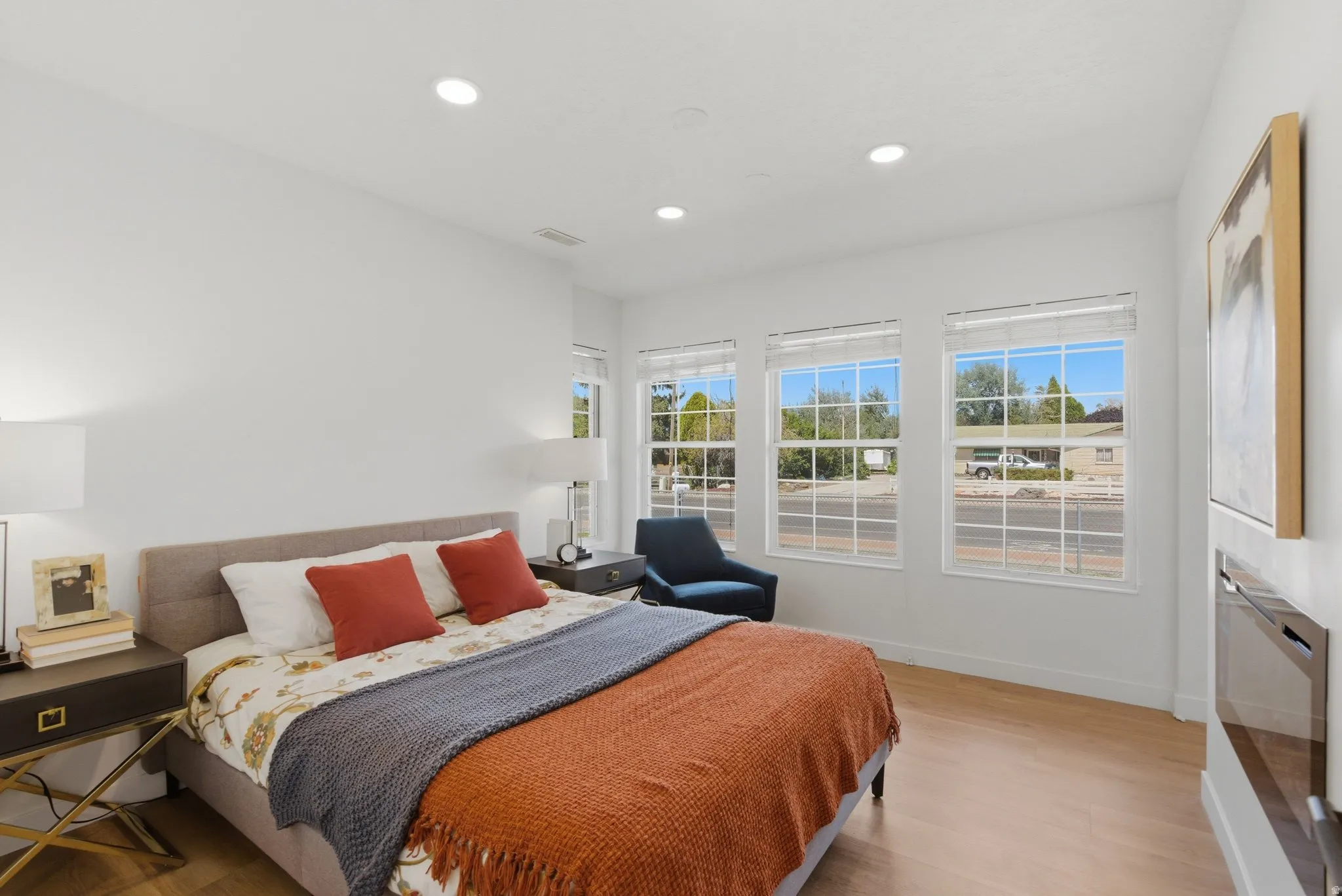 Bedroom featuring three large windows, recessed ceiling lighting, light wood-finish flooring, and white walls