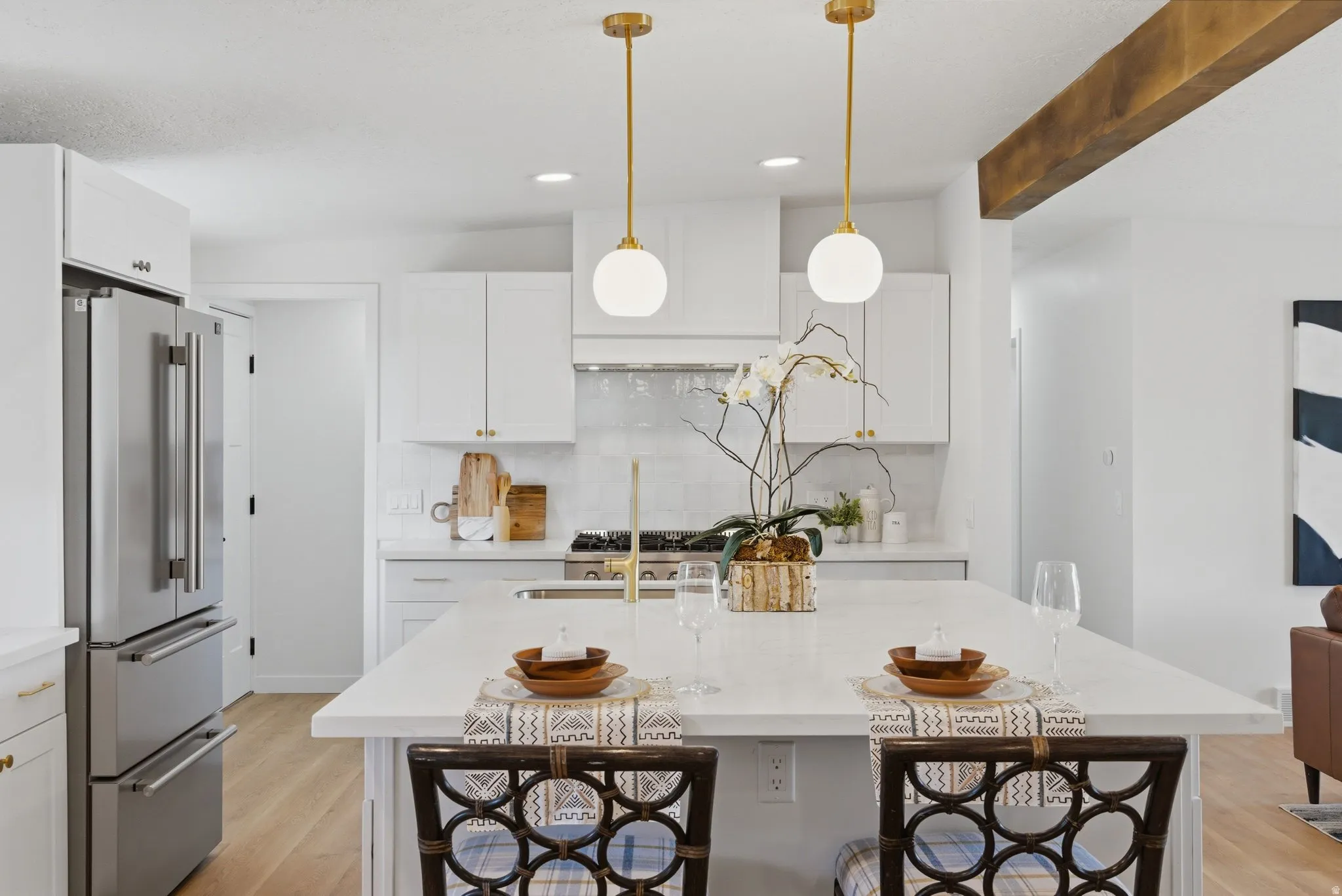 Contemporary kitchen featuring white cabinetry, a large center island with seating, stainless steel appliances, and gold-toned pendant lighting