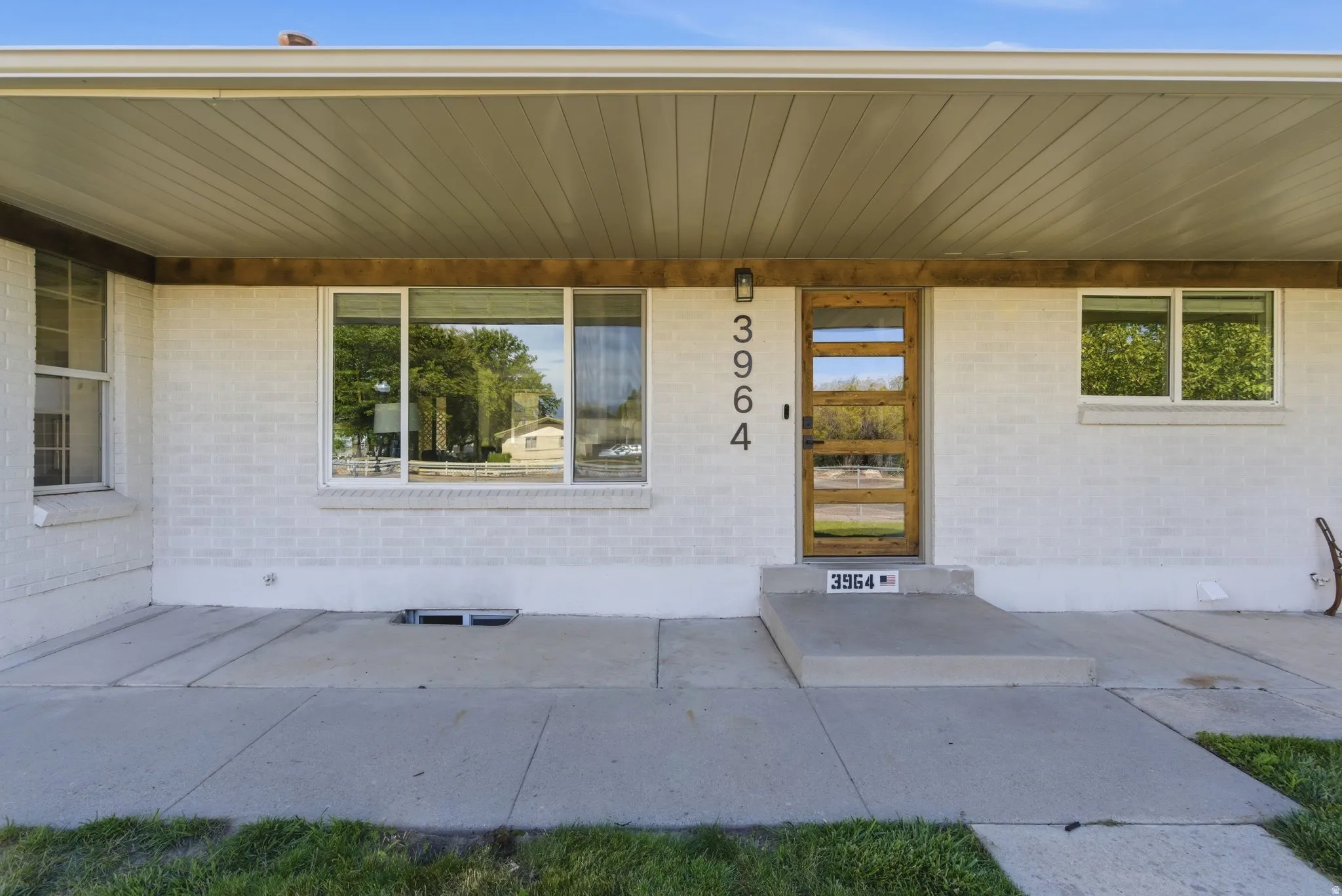 White painted brick exterior featuring a contemporary wood-finish entry door with multiple glass inserts