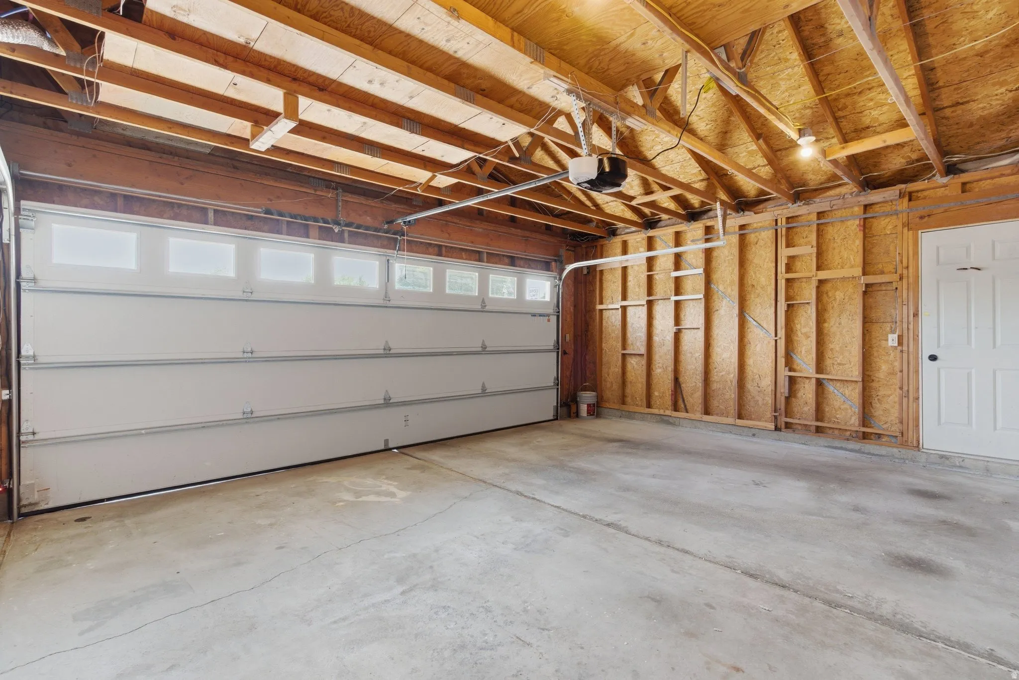 Two-car garage featuring a concrete floor and exposed wood-frame ceiling