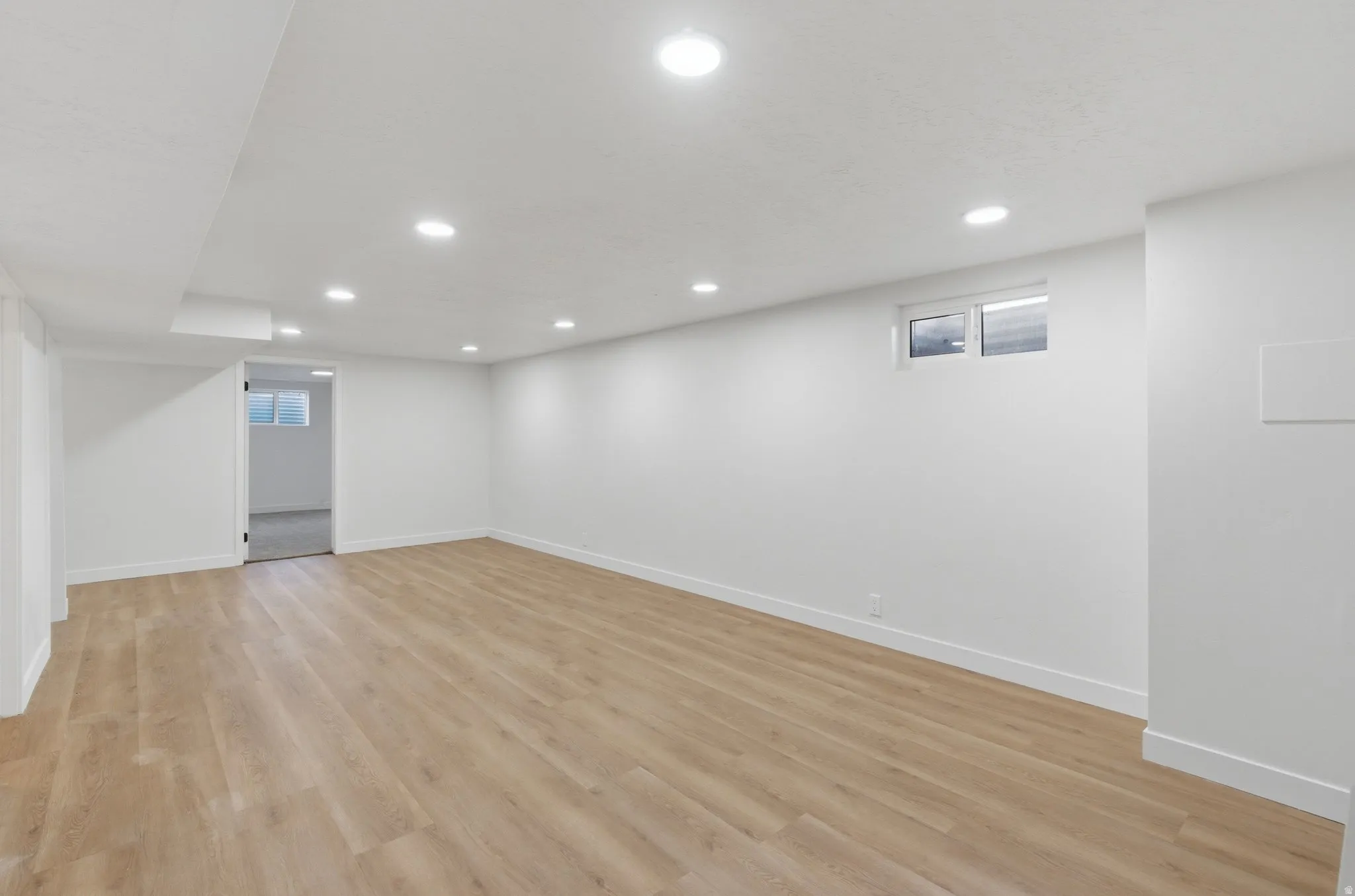 Expansive interior space featuring wood-finish flooring, recessed lighting, and white baseboards