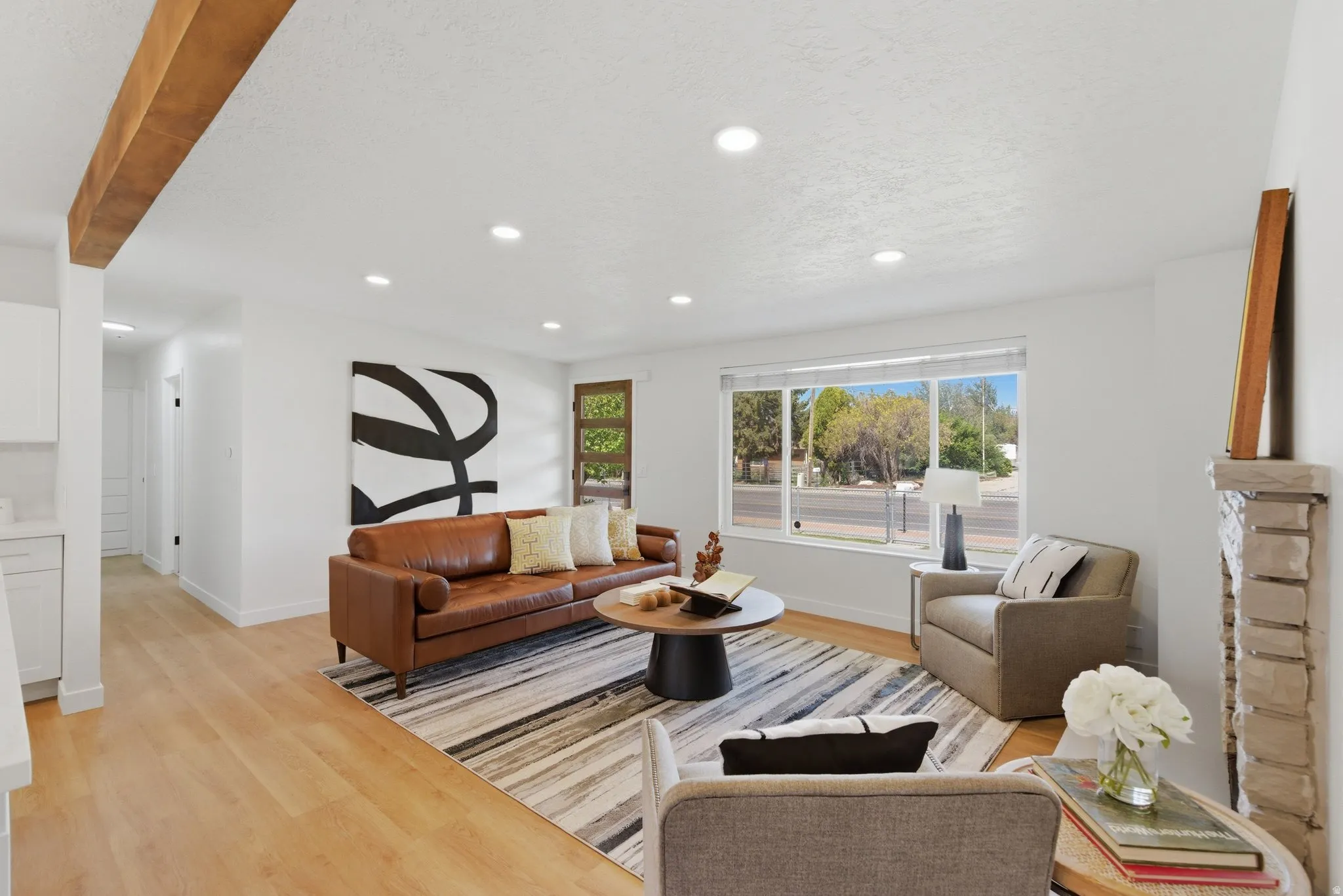 Living area featuring wood-finish flooring, a stone-clad fireplace, and recessed lighting