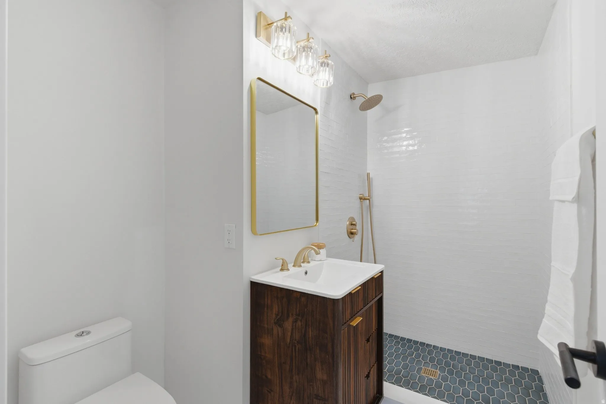 Bathroom featuring a contemporary wood-finish vanity with an integrated sink, gold-tone faucet, and rectangular mirror