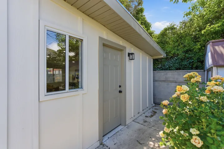 Exterior wall featuring vertical siding, a window, and a door with a contemporary wall sconce