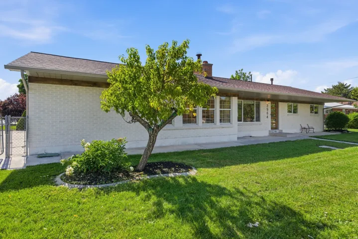 Ranch-style exterior featuring painted brick, a brown shingle roof, and multiple windows