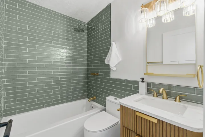 Bathroom featuring a white soaking tub, green subway tile shower surround, and a rain shower head