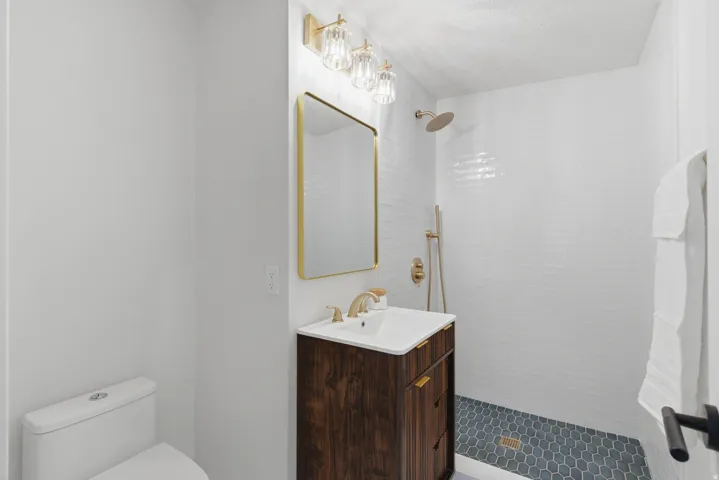 Bathroom featuring a contemporary wood-finish vanity with an integrated sink, gold-tone faucet, and rectangular mirror