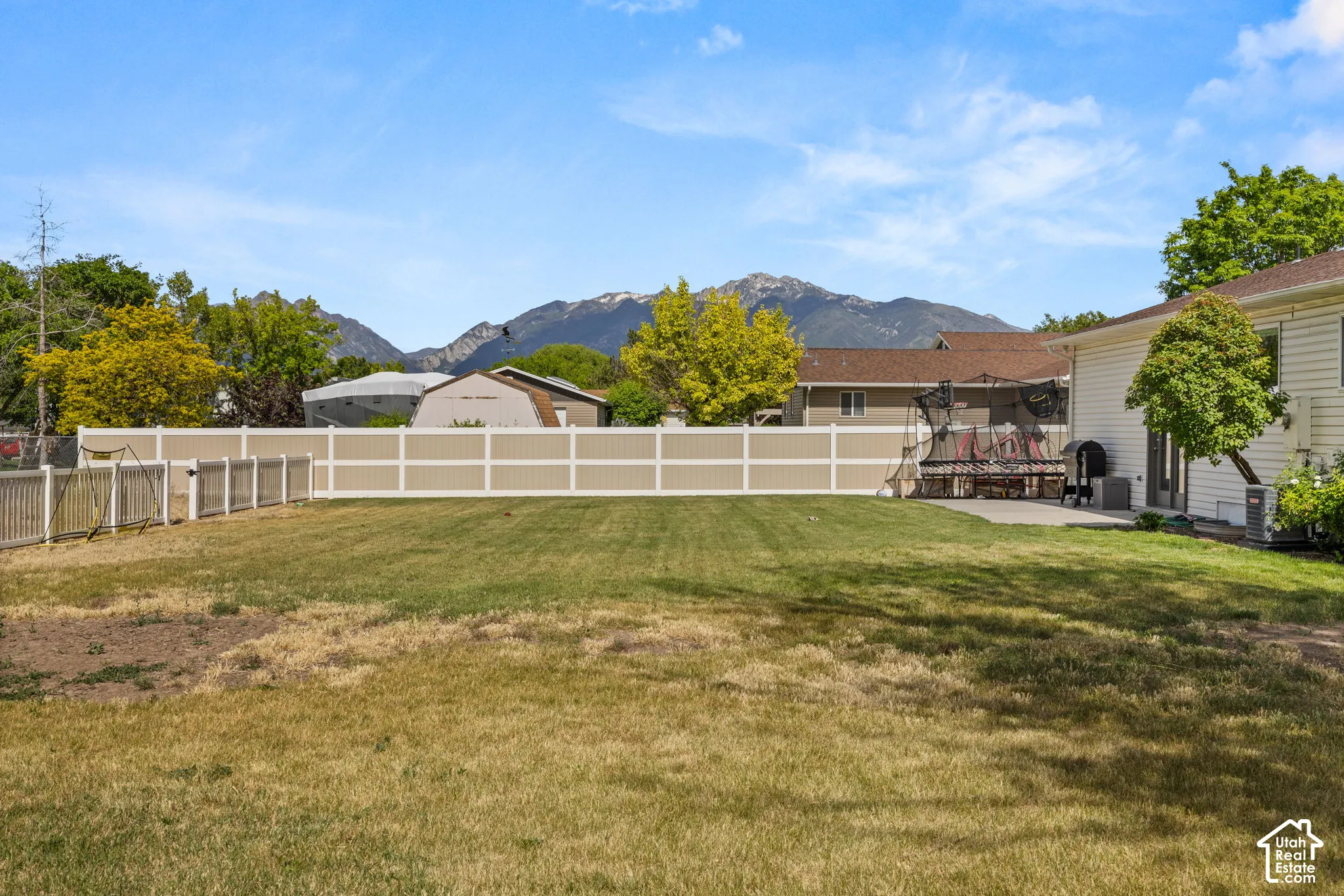 Expansive backyard featuring a partial vinyl privacy fence and a concrete patio