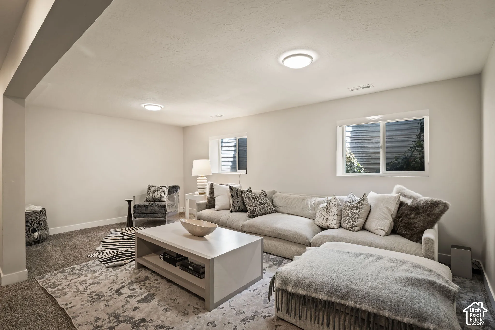 Recessed lighting illuminates this room featuring wall-to-wall carpeting and neutral wall tones