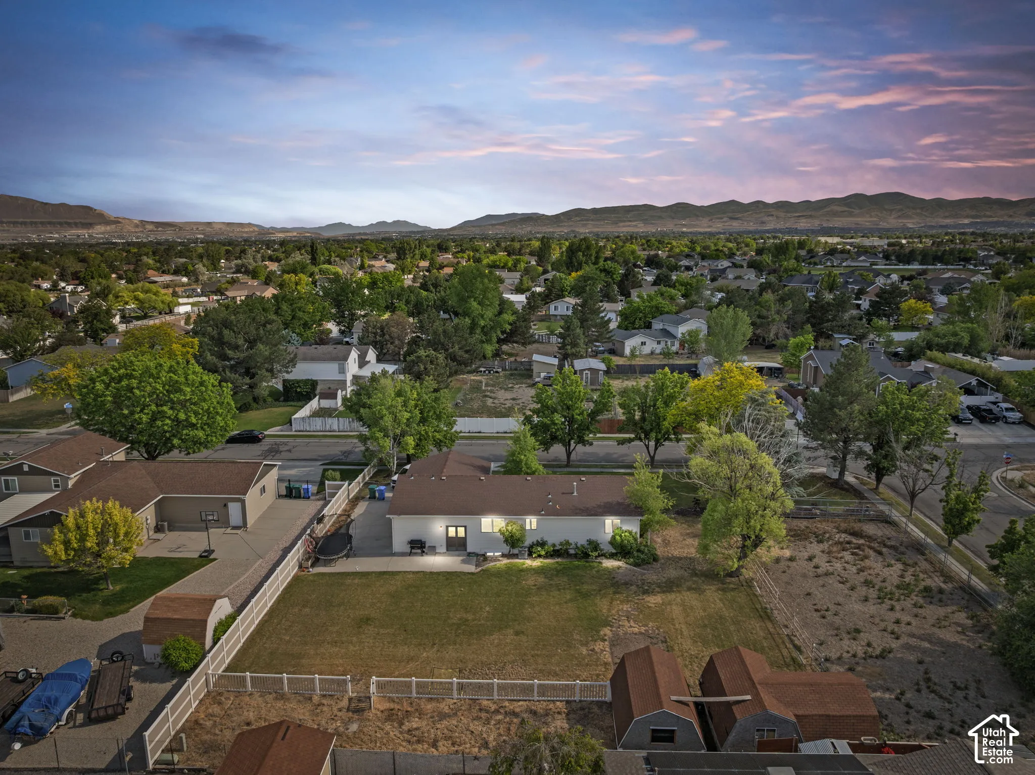 Expansive property featuring a large grassy yard, fenced perimeter, multiple outbuildings, and a paved driveway
