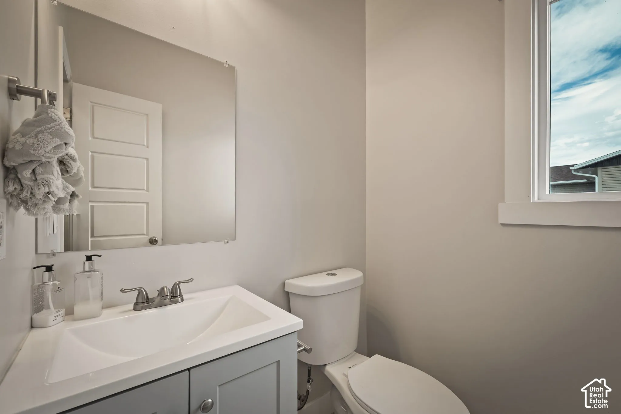 Bathroom featuring a white integrated sink and gray vanity with chrome hardware, coordinating chrome faucet, and a wall-mounted mirror