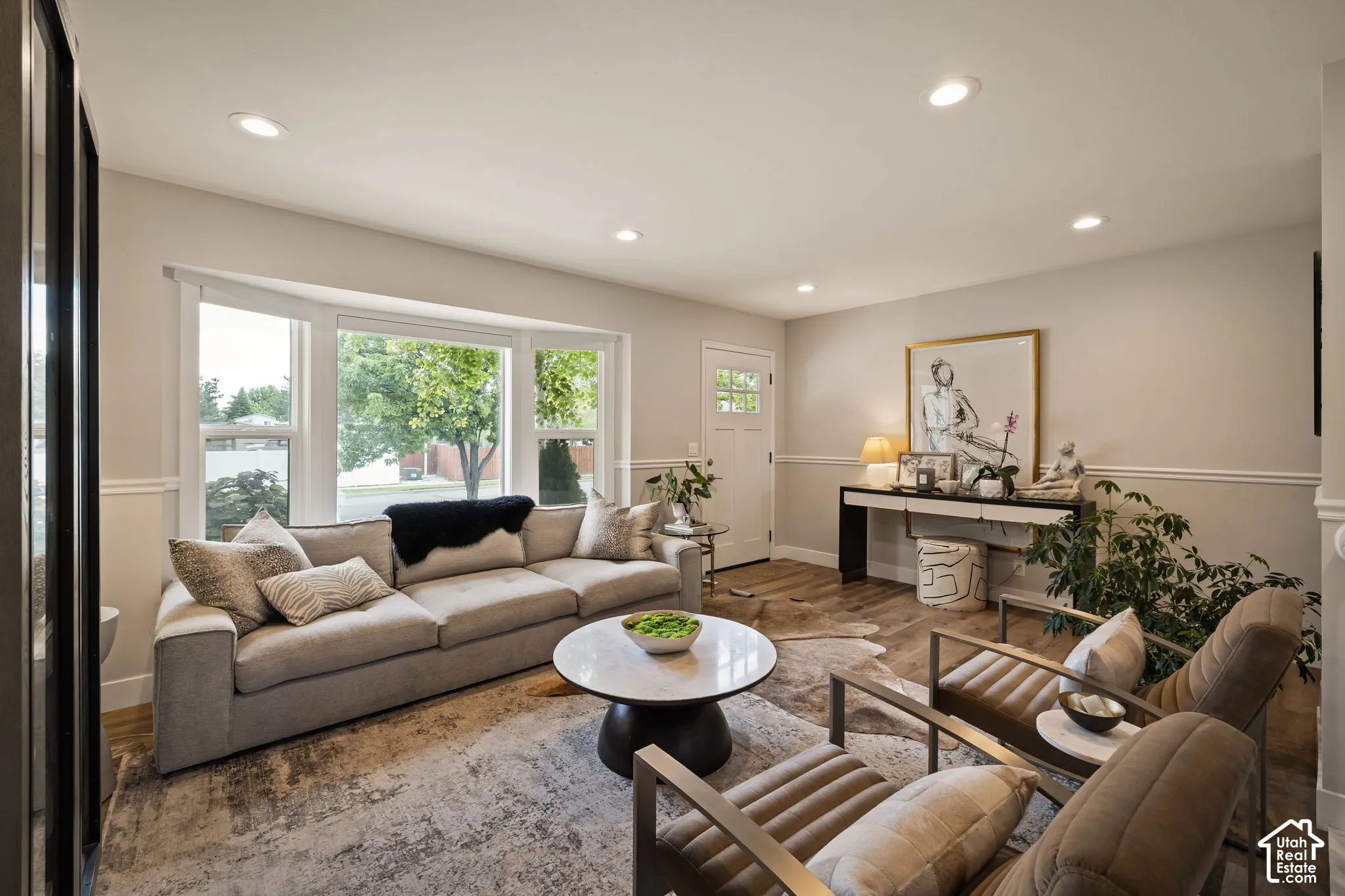 Living space featuring a prominent bay window, recessed lighting, wood-finish flooring, and white baseboards with chair rail molding