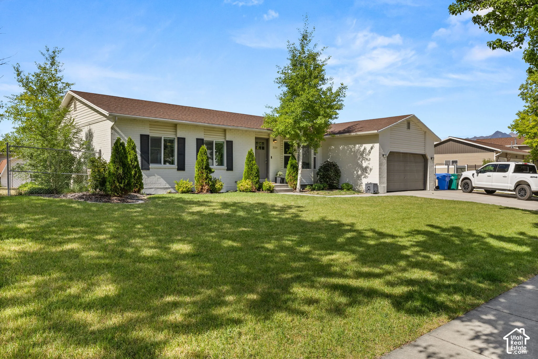 Single-story residence featuring a two-car garage, established landscaping, and a concrete driveway