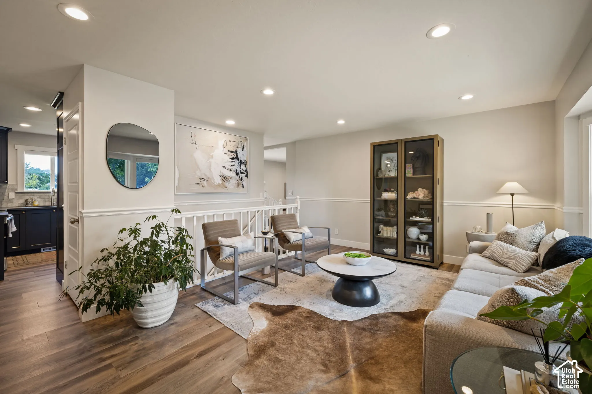 Open-concept living space featuring wood-finish flooring, recessed lighting, white wainscoting, and a white railing