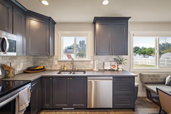 Kitchen featuring dark cabinetry, stone-finish countertops, tile backsplash, and stainless steel appliances