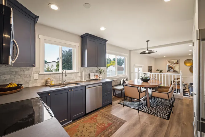 Modern kitchen featuring dark cabinetry, stainless steel appliances, a tile backsplash, and wood-finish flooring