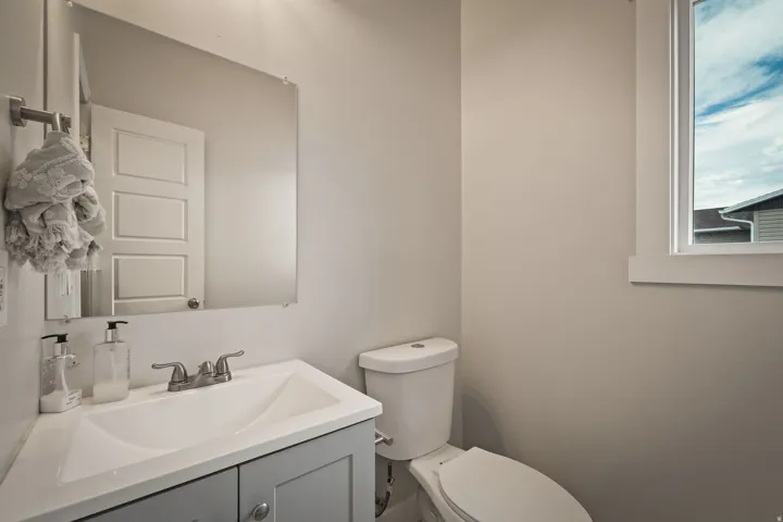 Bathroom featuring a white integrated sink and gray vanity with chrome hardware, coordinating chrome faucet, and a wall-mounted mirror