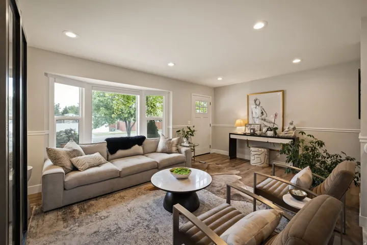 Living space featuring a prominent bay window, recessed lighting, wood-finish flooring, and white baseboards with chair rail molding