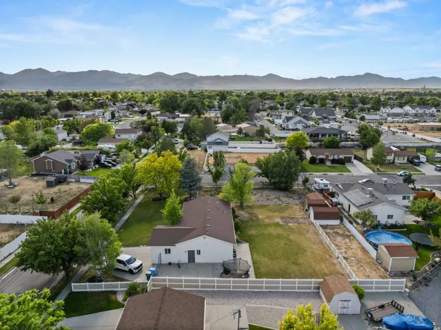 Expansive property featuring a white privacy fence, mature trees, a detached storage shed, and a mountain backdrop