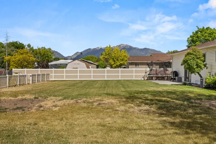 Expansive backyard featuring a partial vinyl privacy fence and a concrete patio