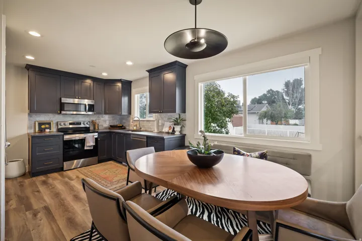 Modern kitchen featuring dark cabinetry with brushed nickel hardware, stainless steel appliances, recessed lighting, and wood-finish flooring