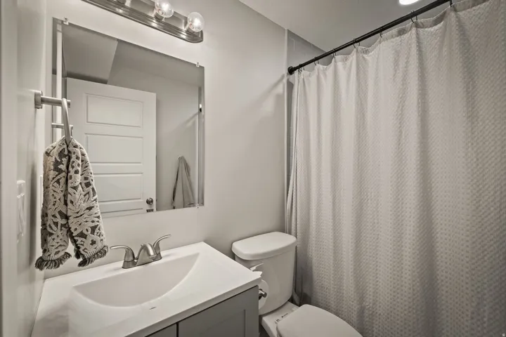 Bathroom featuring a vanity with a white countertop and undermount sink, brushed nickel faucet, wall-mounted mirror, and overhead vanity lighting