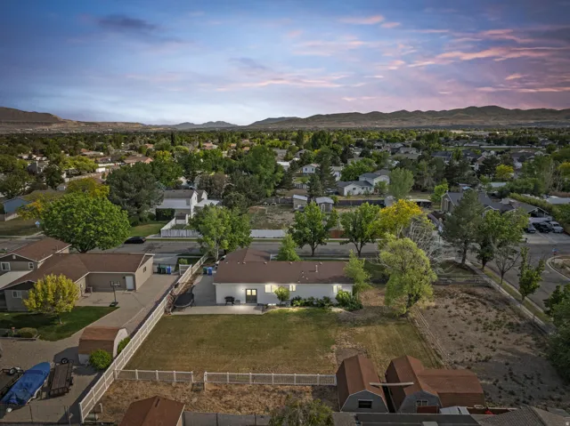 Expansive property featuring a large grassy yard, fenced perimeter, multiple outbuildings, and a paved driveway
