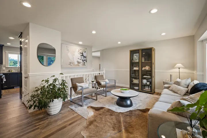 Open-concept living space featuring wood-finish flooring, recessed lighting, white wainscoting, and a white railing