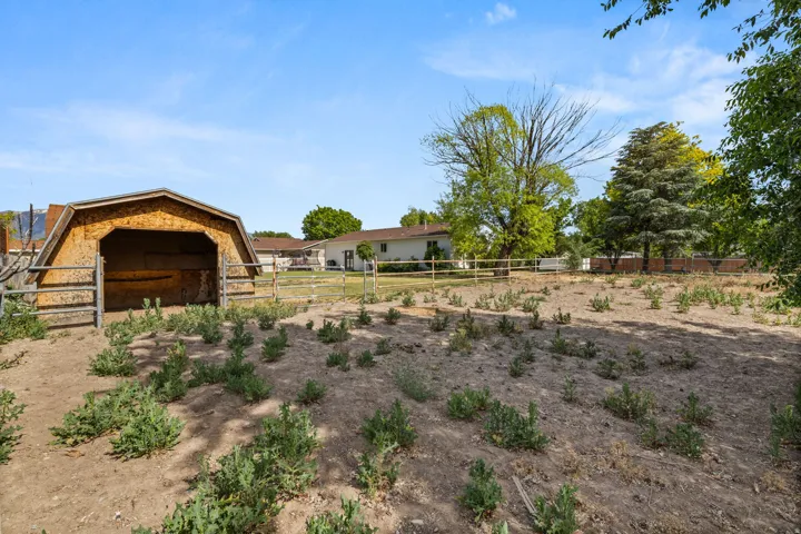 Open-sided barn structure with wood siding and a brown shingle roof