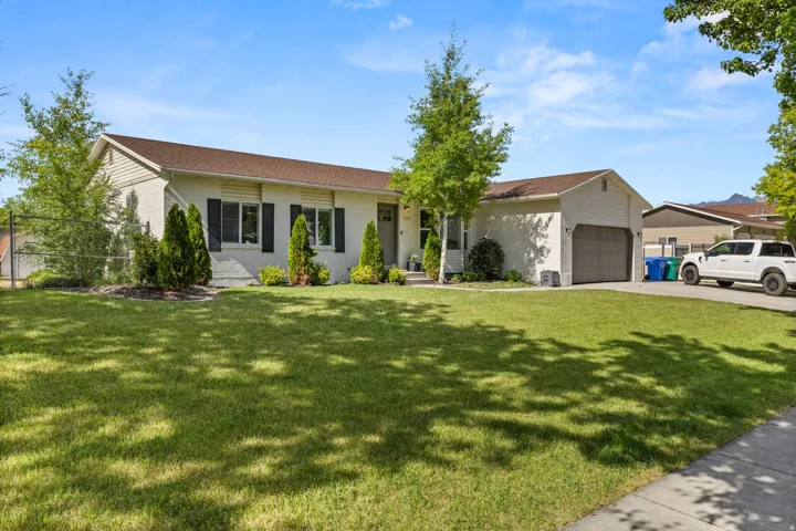 Single-story residence featuring a two-car garage, established landscaping, and a concrete driveway