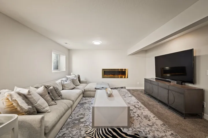 Recessed electric fireplace with a brass-toned frame, light gray walls, and a carpeted floor
