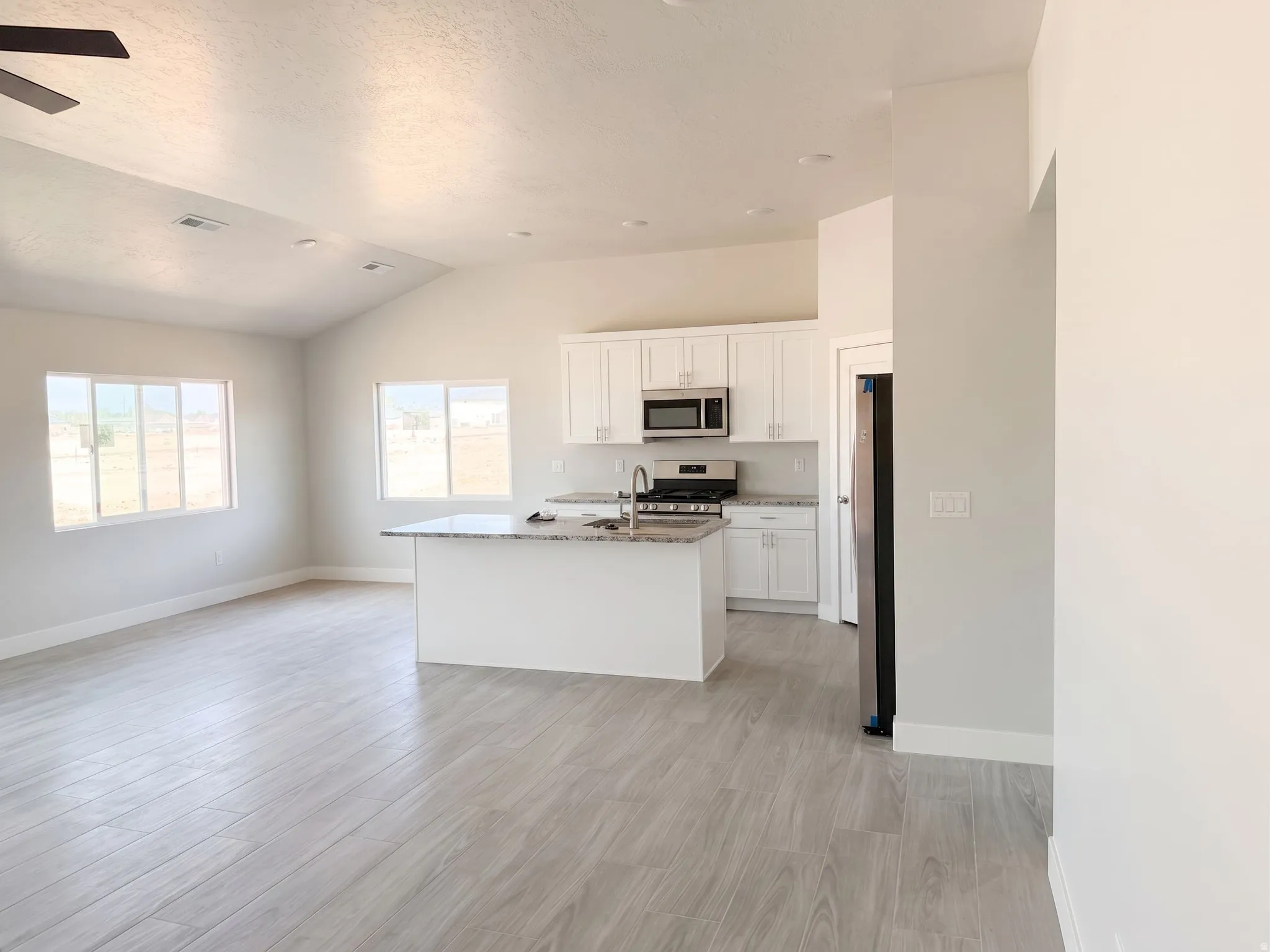 Open-concept living area with vaulted ceilings, wood-finish flooring, and recessed lighting
