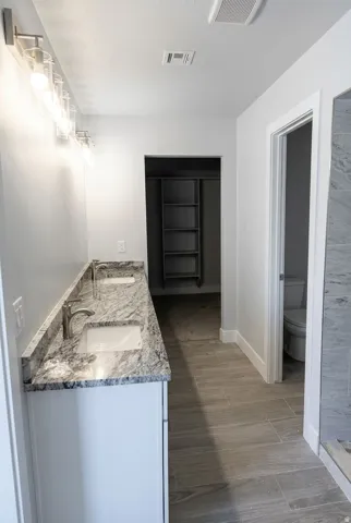 Dual vanity with undermount sinks, stone countertop, and contemporary fixtures