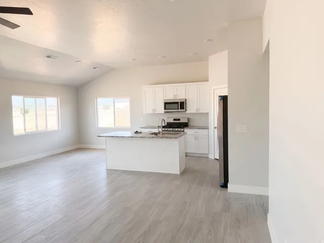 Open-concept living area with vaulted ceilings, wood-finish flooring, and recessed lighting