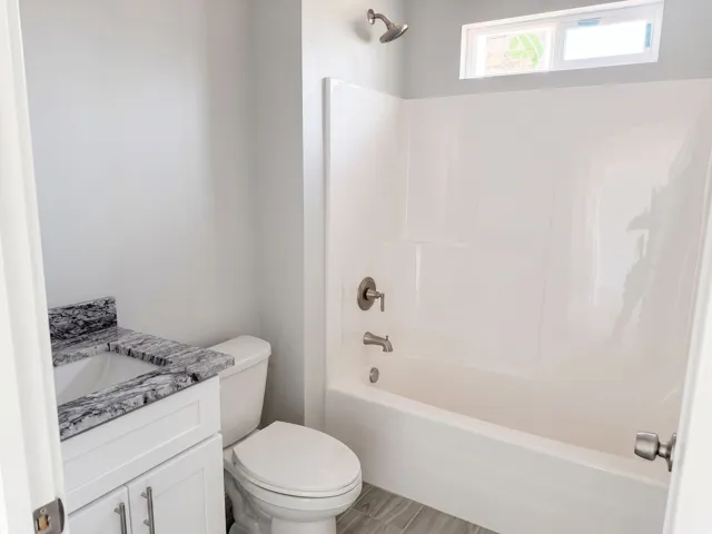 Vanity with stone countertop, undermount sink, and white cabinetry