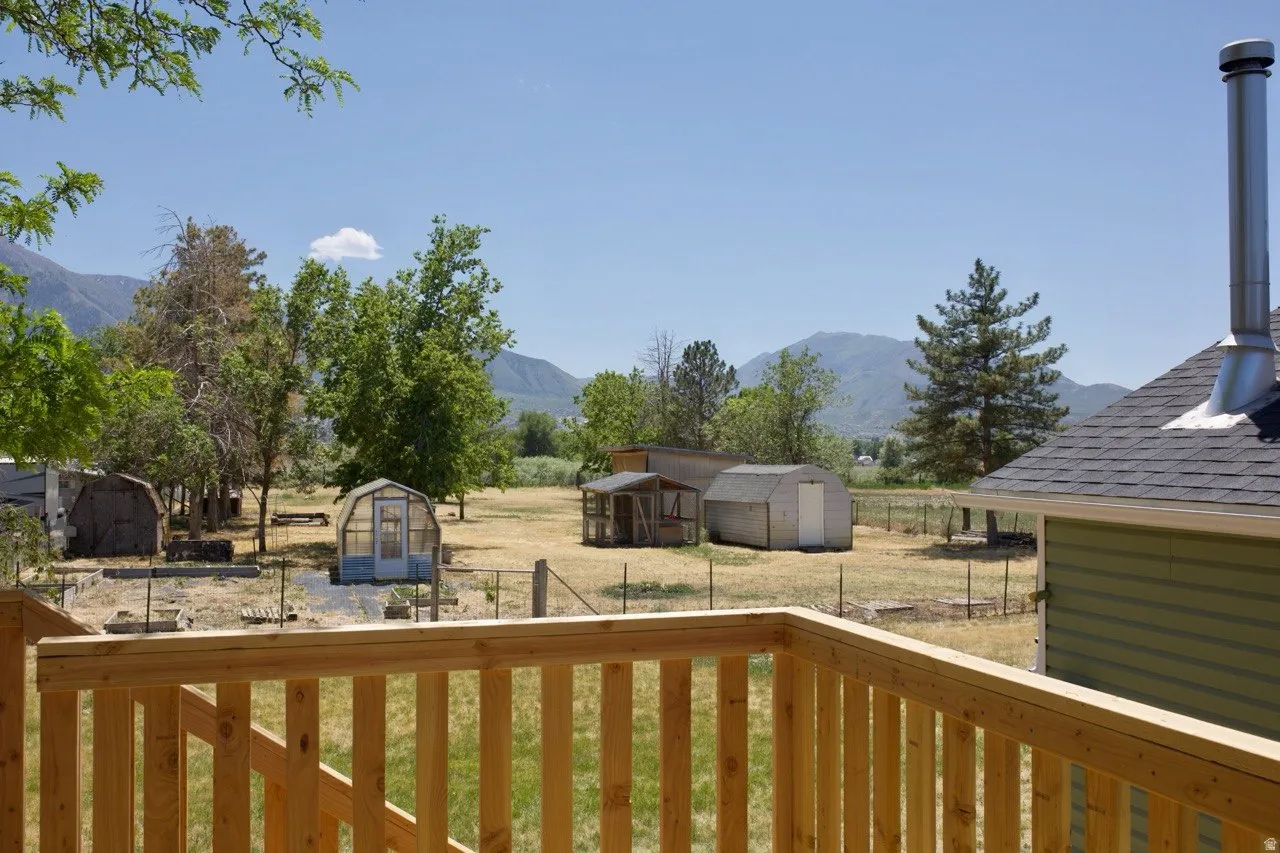 off of Primary Bedroom, Expansive outdoor space featuring a wooden deck railing, multiple outbuildings, and distant mountain scenery