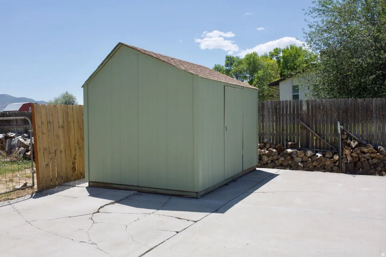 Gable-roof storage shed with a panel siding exterior and shingle roofing