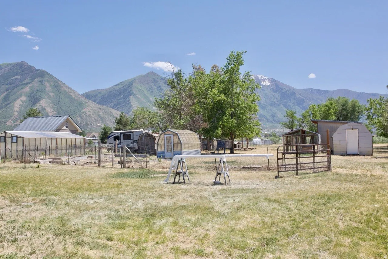 Expansive property featuring multiple greenhouses and outbuildings set against a mountain backdrop