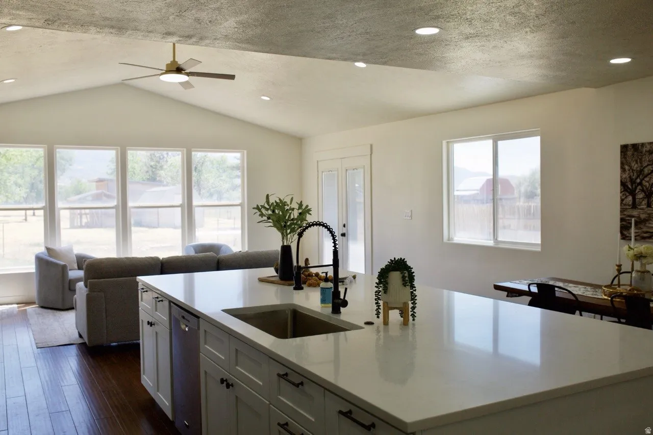 Spacious kitchen island featuring a white countertop and undermount sink with a matte black faucet